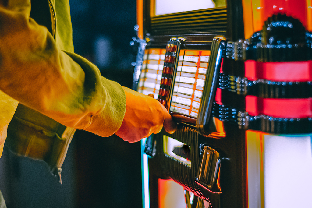 Male hand pushing buttons to play song on old Jukebox, selecting records