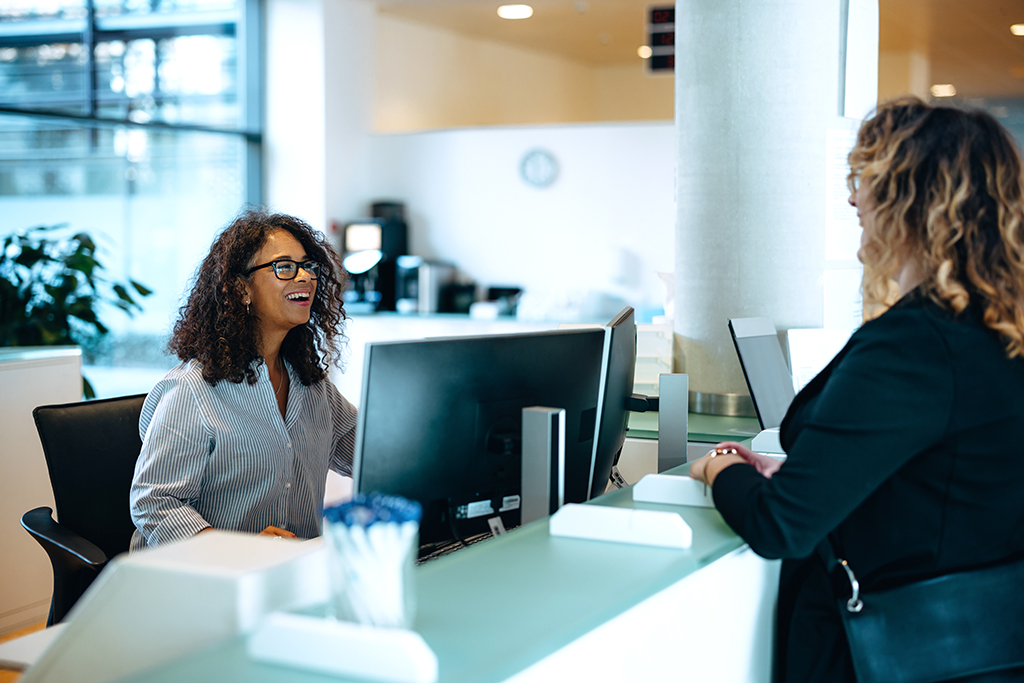 Receptionist assisting a woman standing at front desk