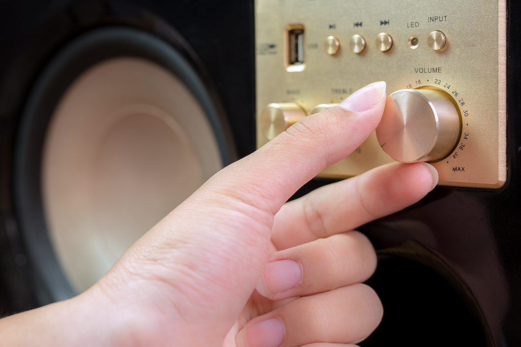 close up of a hand adjusting the speaker volume